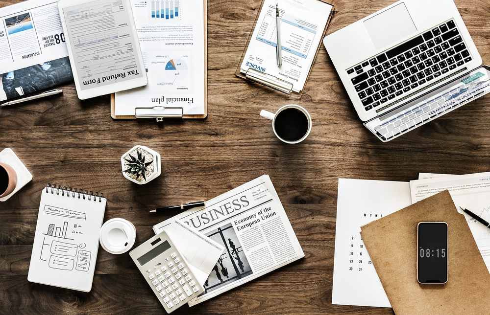 Ordinateur portable, documents, calculatrice, café, agenda sur table en bois