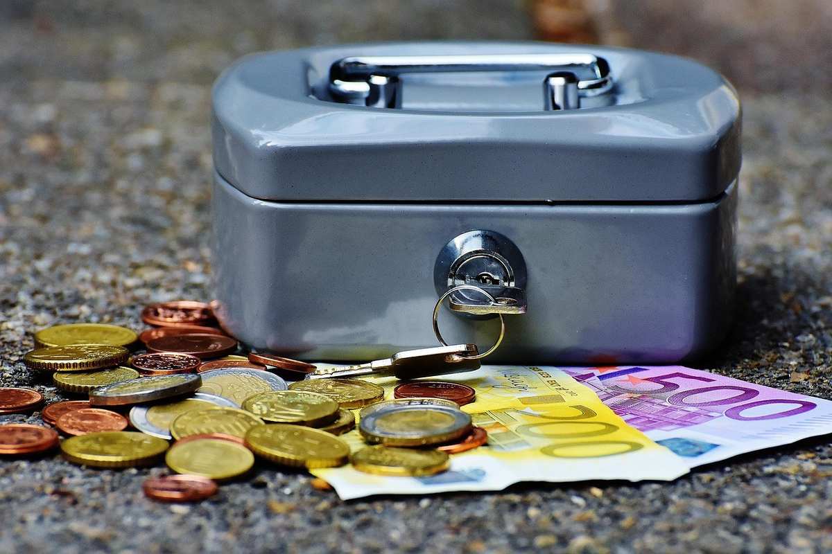Boîte à argent avec pièces et billets sur le sol Boîte à argent avec pièces et billets sur le sol