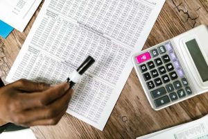 Une main écrit sur un tableau de chiffres avec une calculatrice