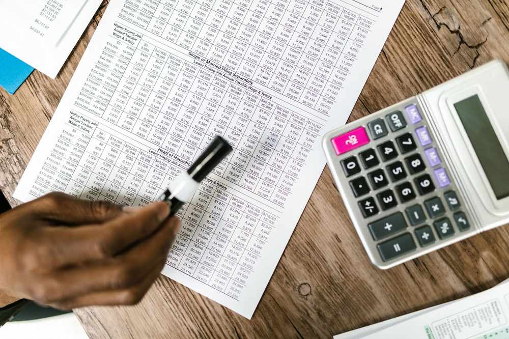Une main écrit sur un tableau de chiffres avec une calculatrice